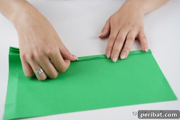 Folding a green piece of paper into a zig zag for making a 3d tree