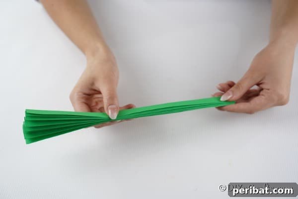 Folding a piece of green paper to create a tree for a 3d card