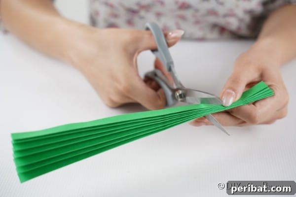 Cutting a green paper fan piece into smaller pieces to create a green 3d Christmas tree
