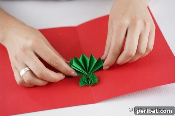 Gluing the green tree trunk pieces to the inside of the red card for Christmas