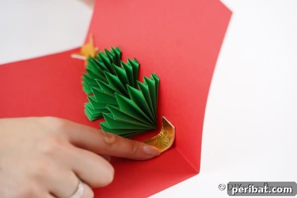 Gluing a gold star at the top of a 3D Christmas tree card