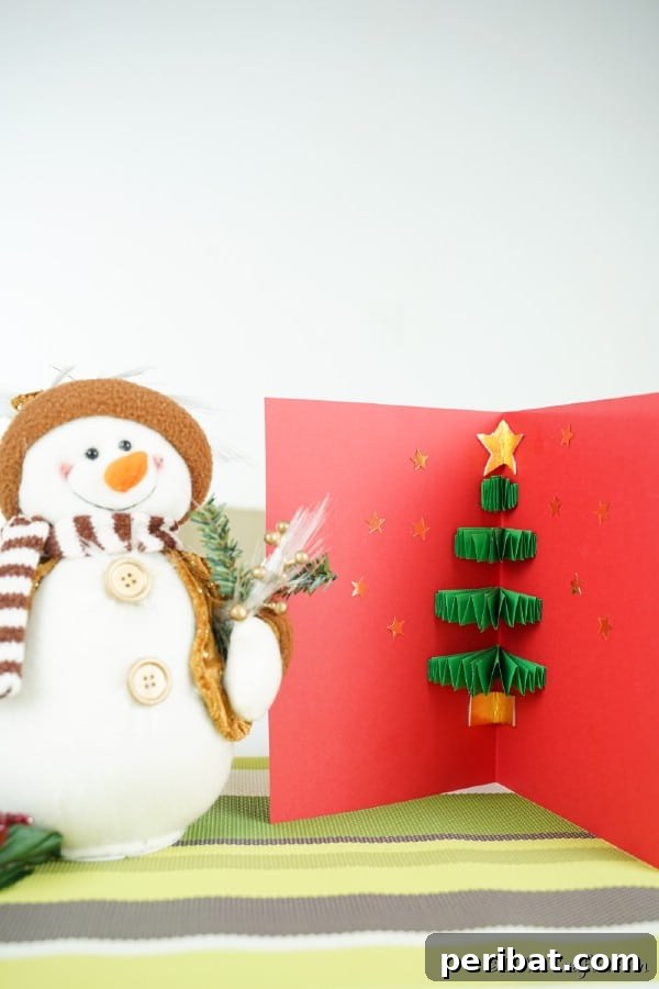 A 3D Christmas tree card displayed next to a snowman figurine