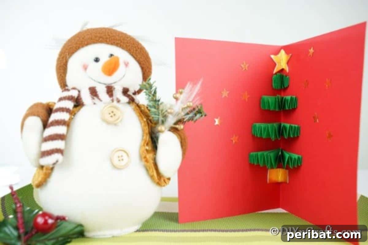 A red and green 3D Christmas tree card sitting next to a toy snowman