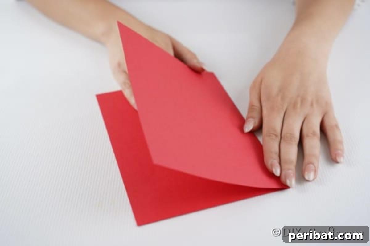 Folding red paper in half to create a 3d card for Christmas