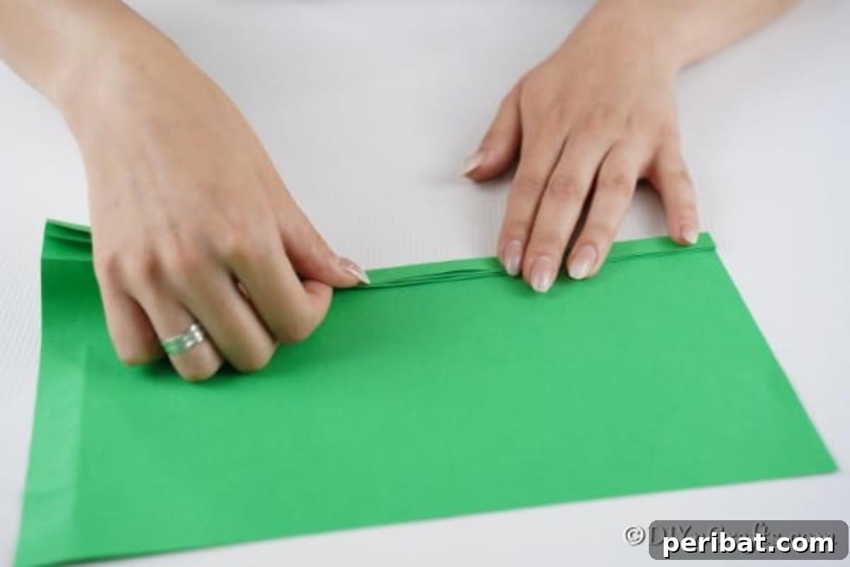Folding a green piece of paper into a zig zag for making a 3d tree