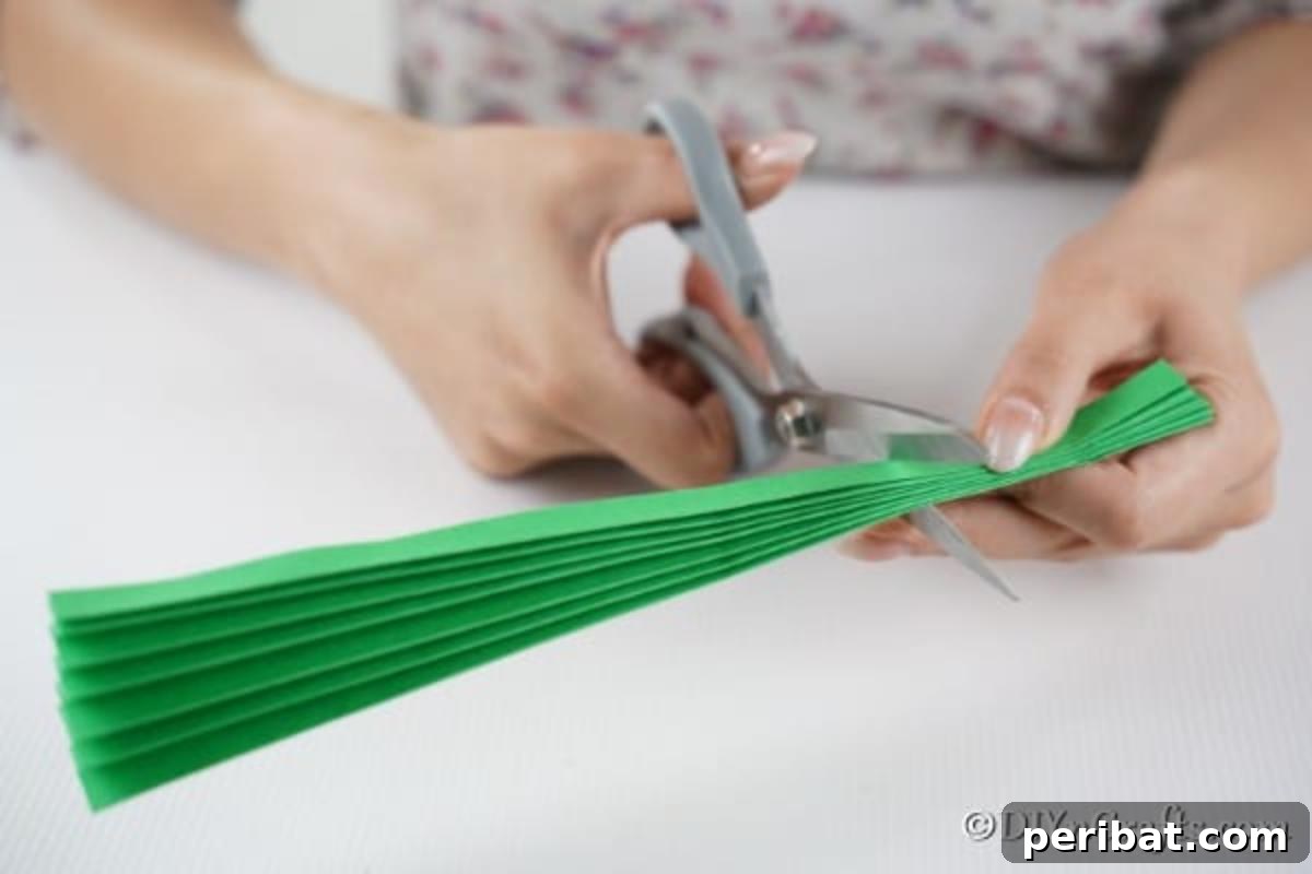 Cutting a green paper fan piece into smaller pieces to create a green 3d Christmas tree