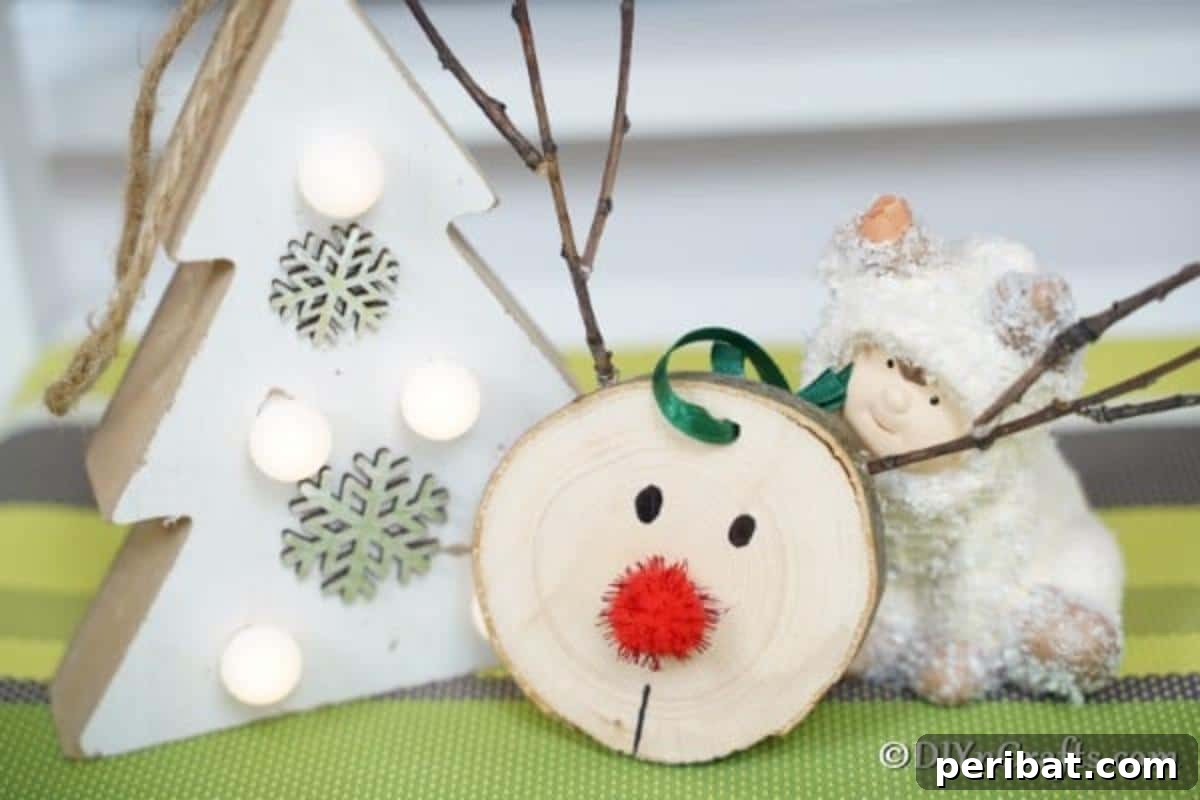 A finished wood slice reindeer ornament elegantly displayed on a green table next to a miniature white holiday tree.