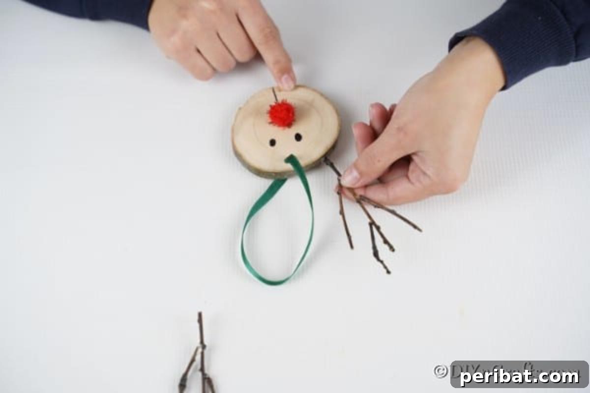 Attaching small twig branches to the top of the wood slice with hot glue to form the reindeer's antlers.