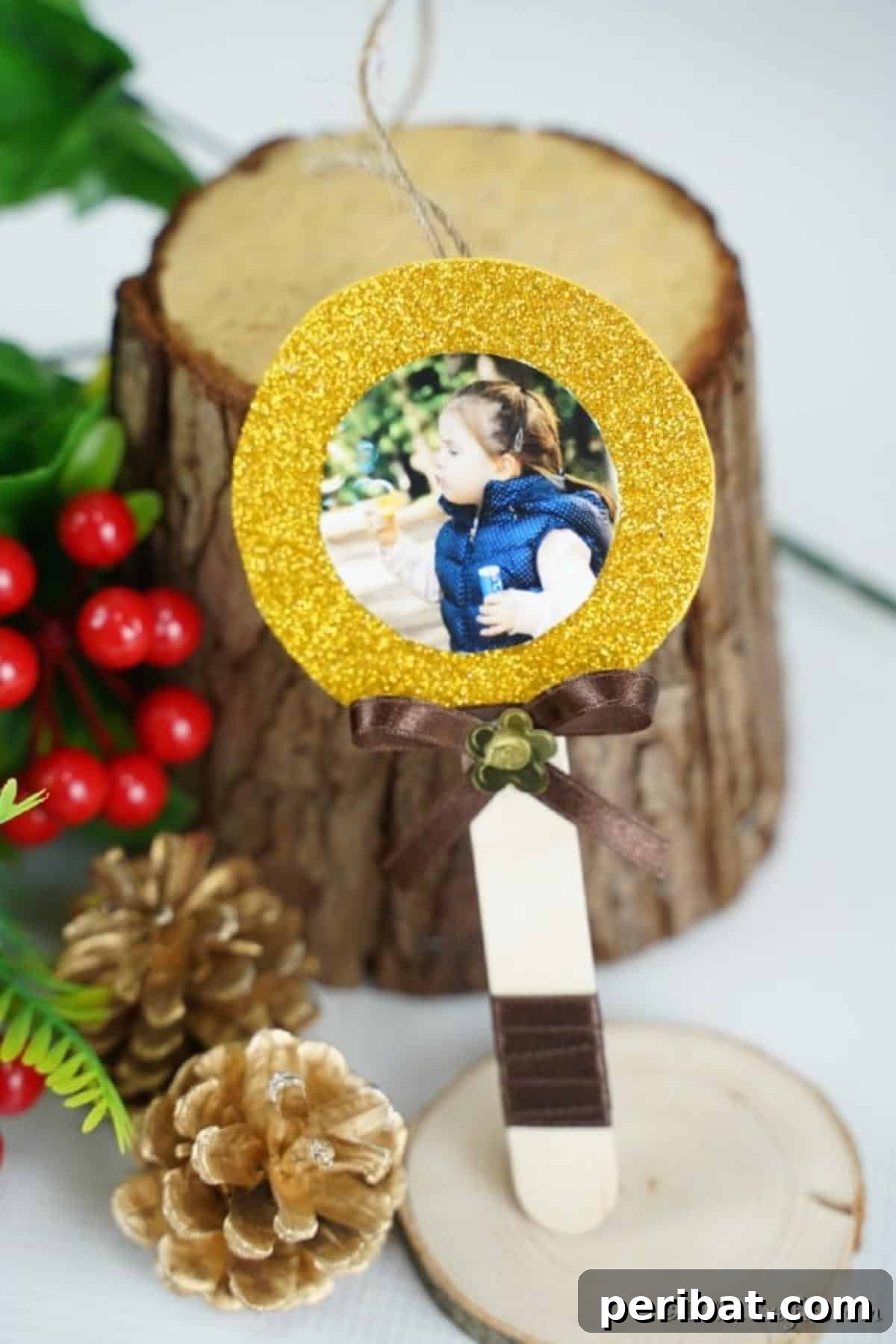 Sweet Memories: Craft Stick Photo Lollipops 12 A charming craft stick lollipop photo ornament, complete with a ribbon bow and hanging loop, displayed on a holiday tree, ready to brighten up any festive display.