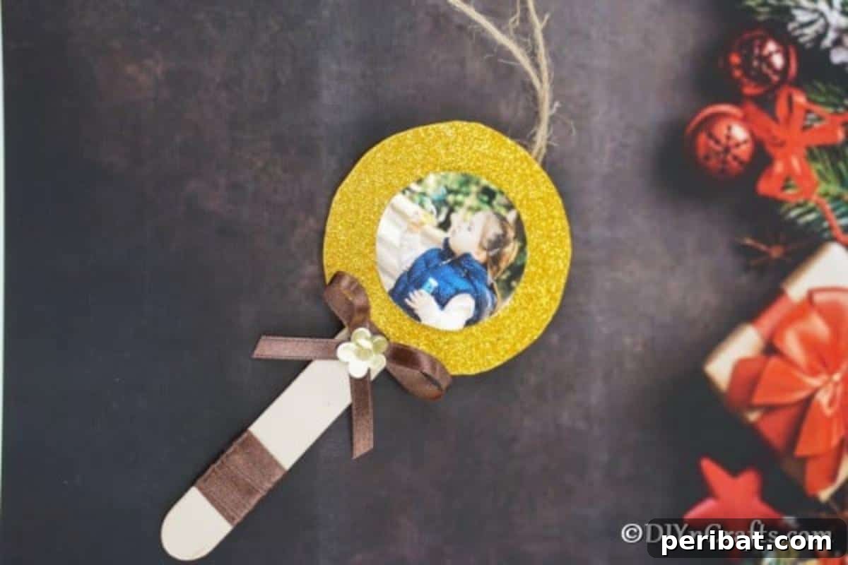 Sweet Memories: Craft Stick Photo Lollipops 5 A charming lollipop photo ornament displayed on a sleek black surface, surrounded by festive holiday decorations, emphasizing its elegance and homemade appeal.