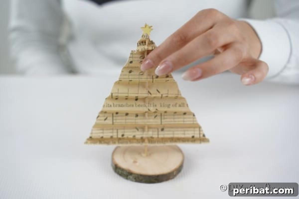 Melody-Folded Christmas Tree 13 The concluding step: attaching the crafted tree to its wooden slice base, making it ready for display.