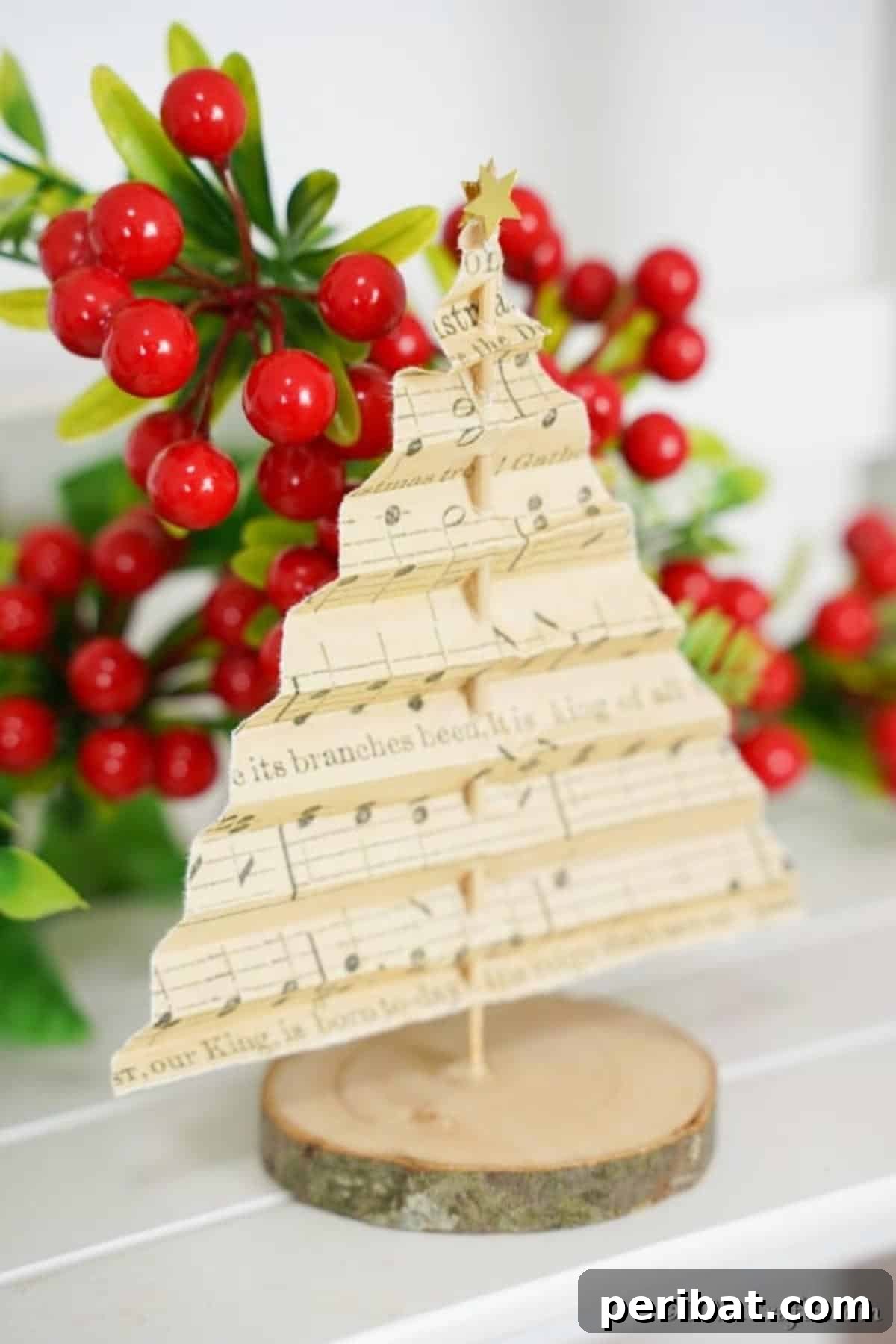 Melody-Folded Christmas Tree 5 A beautifully crafted paper music sheet tree decoration resting on a mantle, accented by vibrant holly berries in the background, exuding a classic Christmas feel.