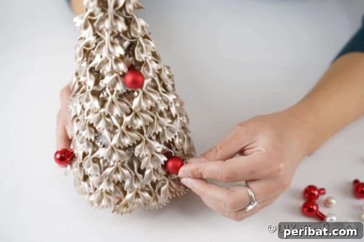 Creative Pasta Christmas Ornaments 17 Delicately adding miniature ornaments to the pasta Christmas tree, bringing festive color and sparkle to the handmade creation.
