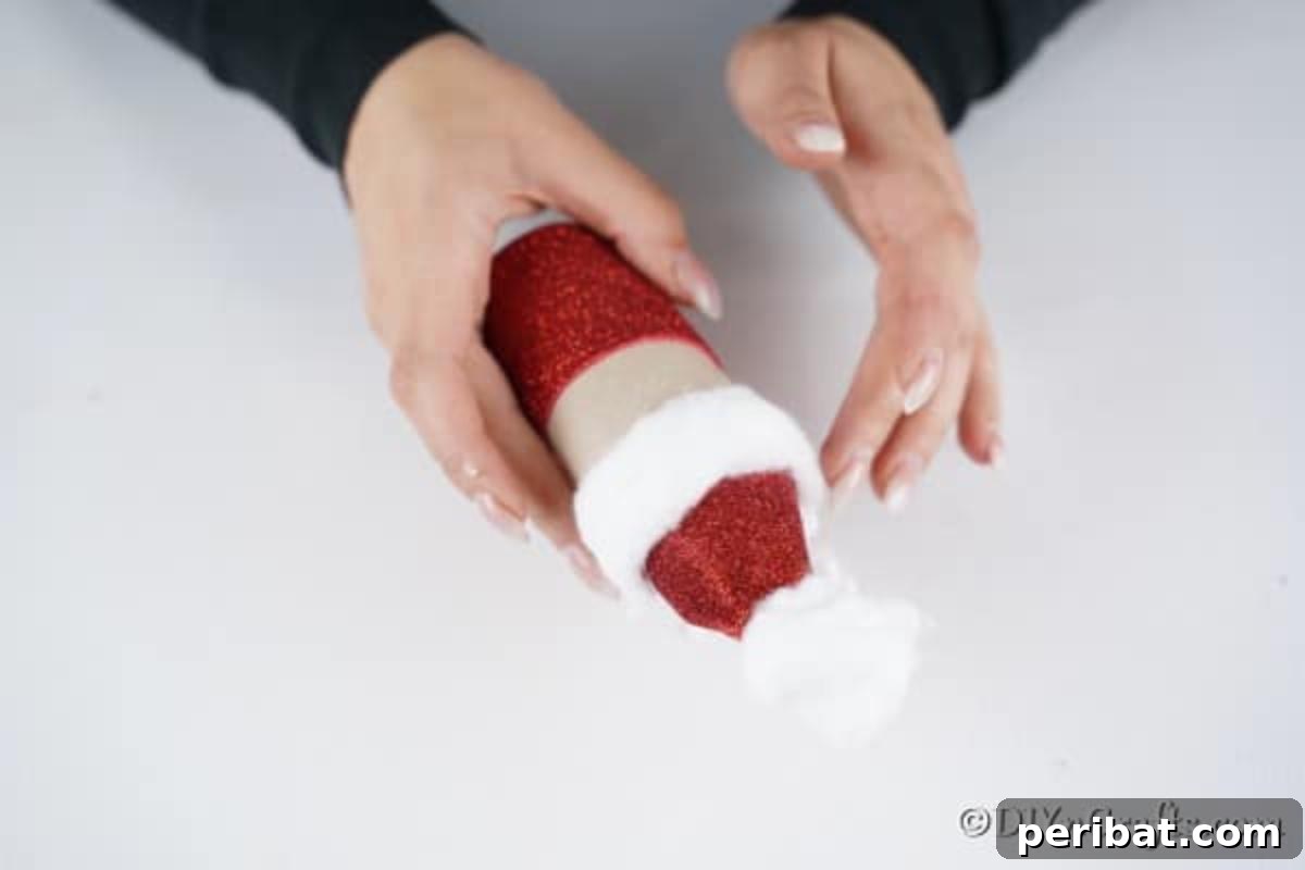 Upcycled Toilet Roll Santa Snowman and Elf for Kids 17 Adding soft cotton strips to create Santa's voluminous white hair around the hat and a full, fluffy beard below his face.