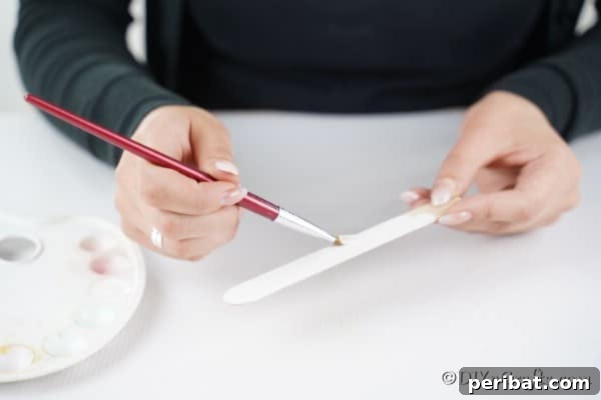 Painting craft sticks for a snowman ornament