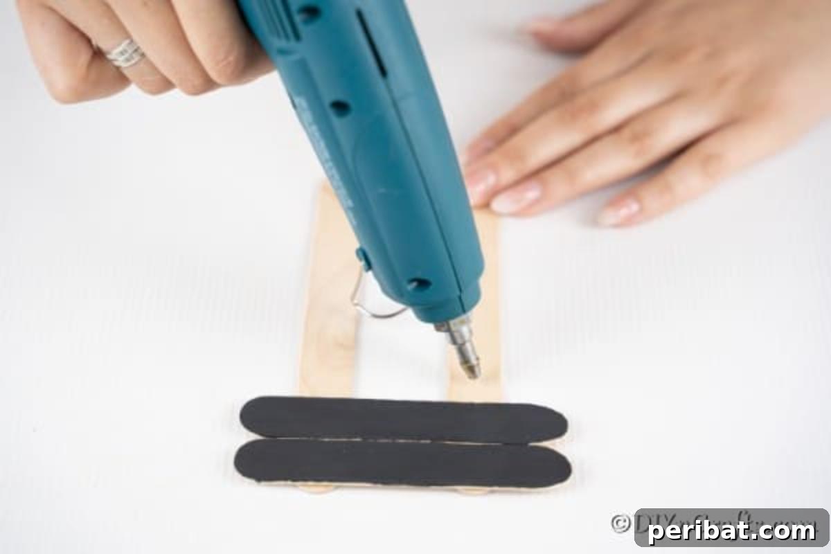 Gluing black craft sticks to the ornament
