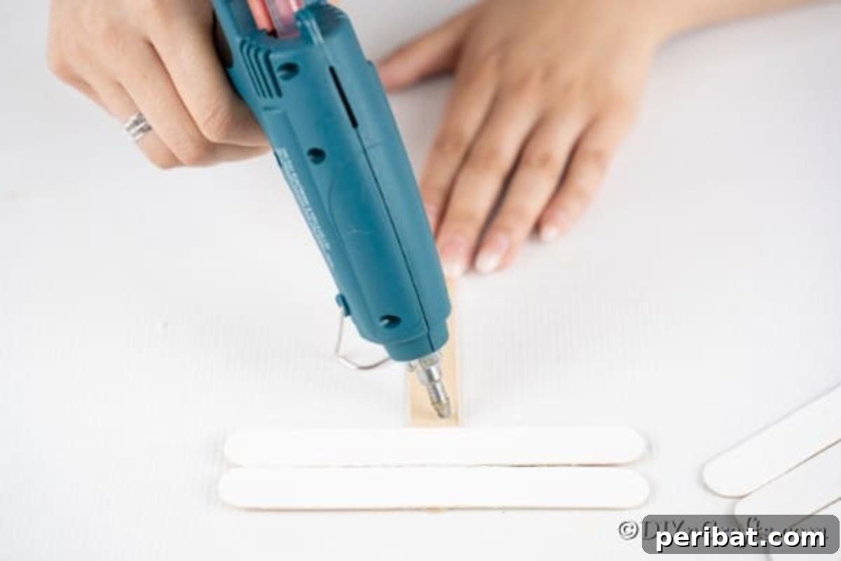 Adding white craft sticks to create snowman face