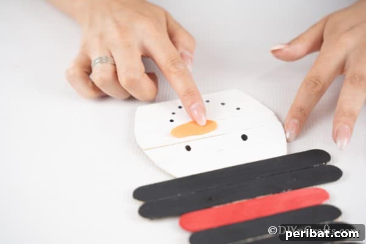 Adding an orange carrot nose to the snowman