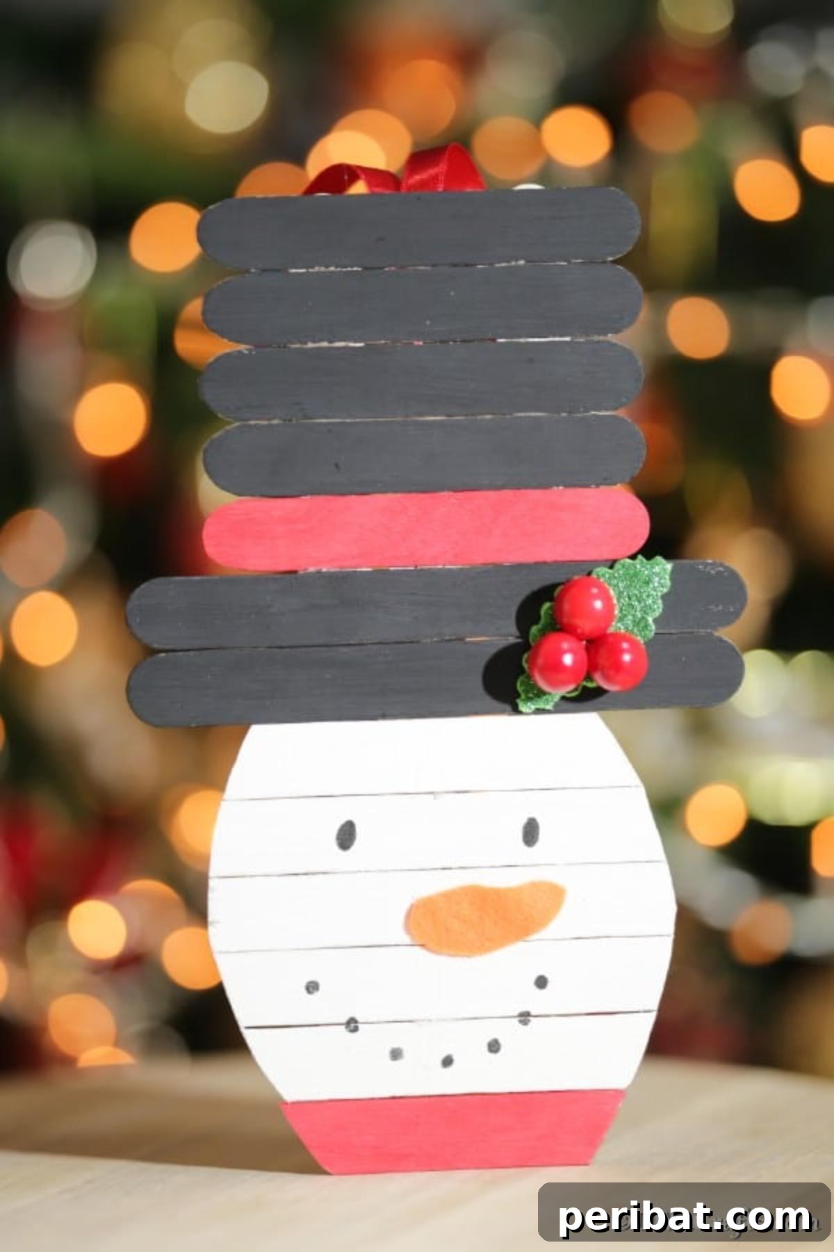 Up close picture of a craft stick snowman in front of a Christmas tree