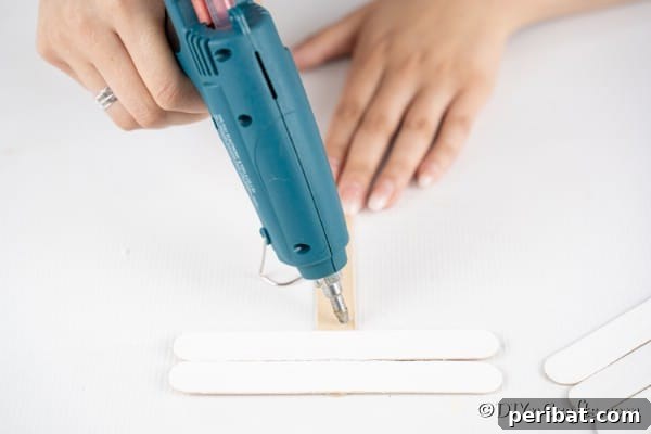 Adding white craft sticks to create snowman face