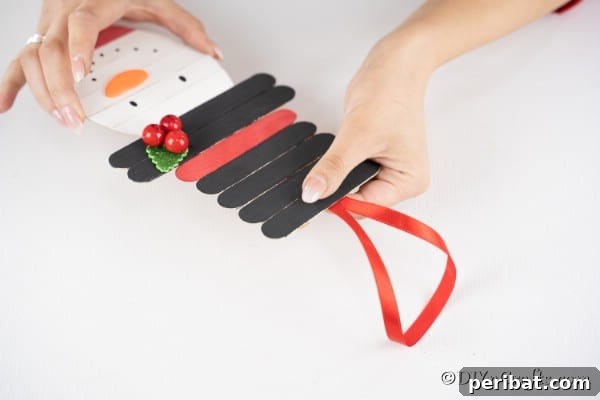 Adding a loop of ribbon to hang the snowman craft