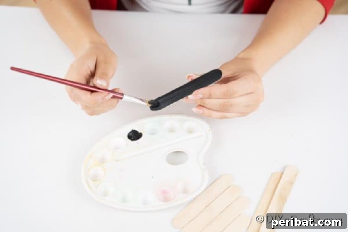 Painting craft sticks black for making a snowman