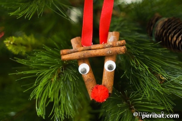 A cinnamon stick reindeer ornament hanging in a Christmas tree