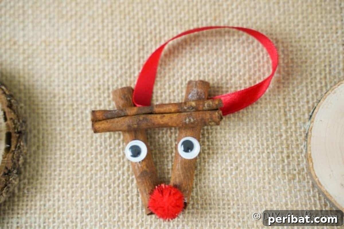 A cinnamon stick reindeer ornament laying on a brown cloth