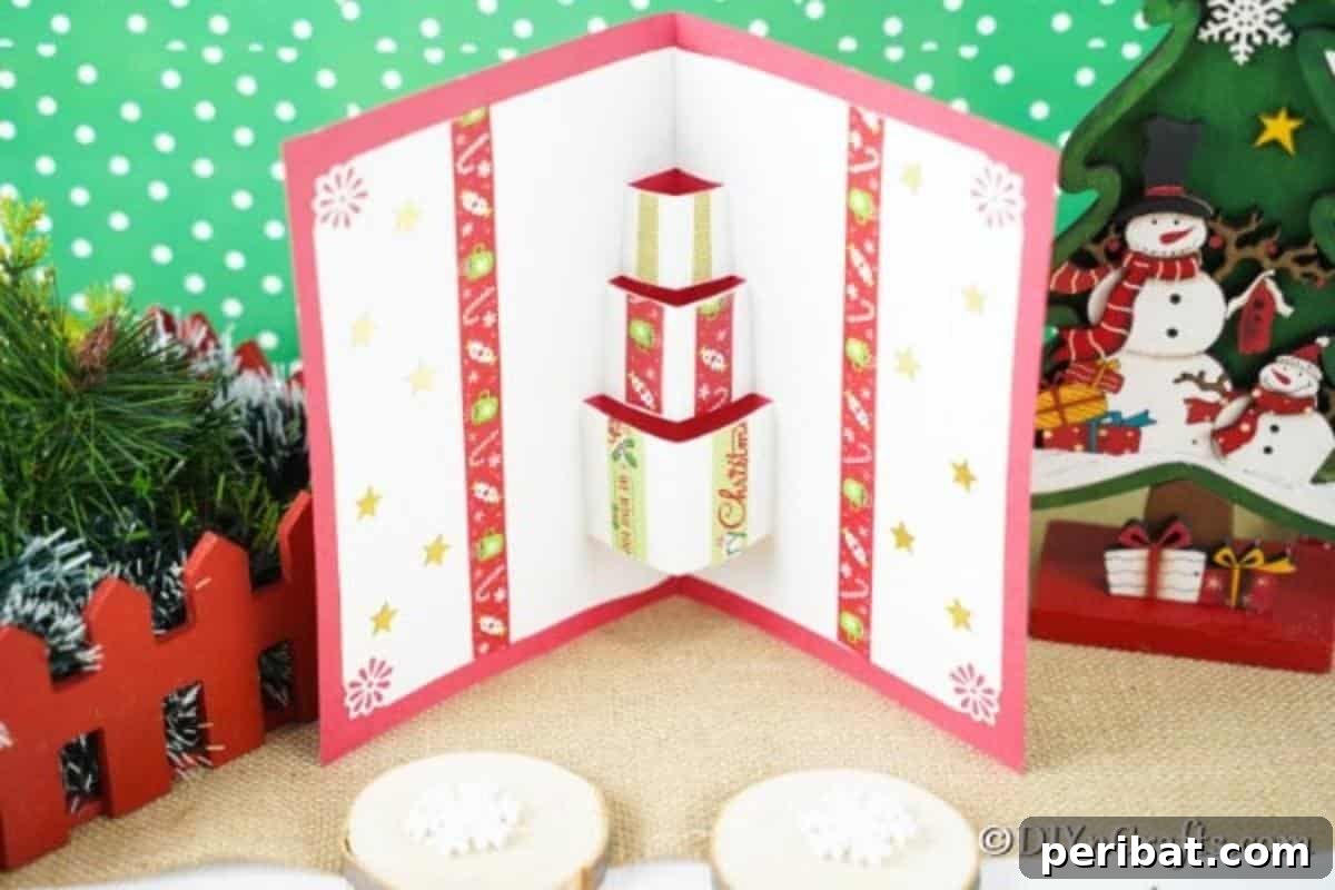 A gift box 3D Christmas cards craft displayed with holiday decor in front of a green and white background