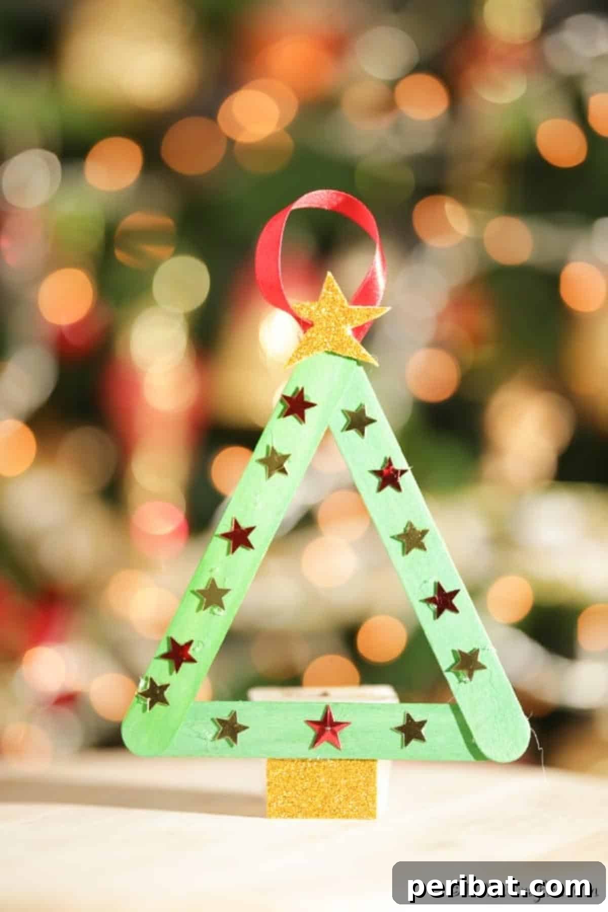 A craft stick Christmas tree displayed in front of a real tree