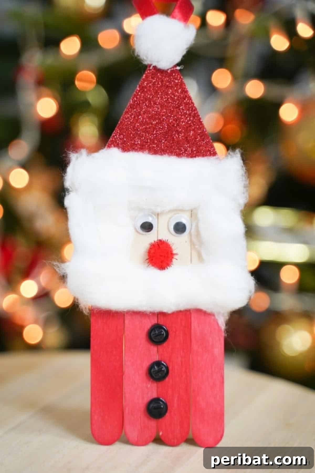 A Craft Stick Santa Claus on a table in front of a Christmas tree