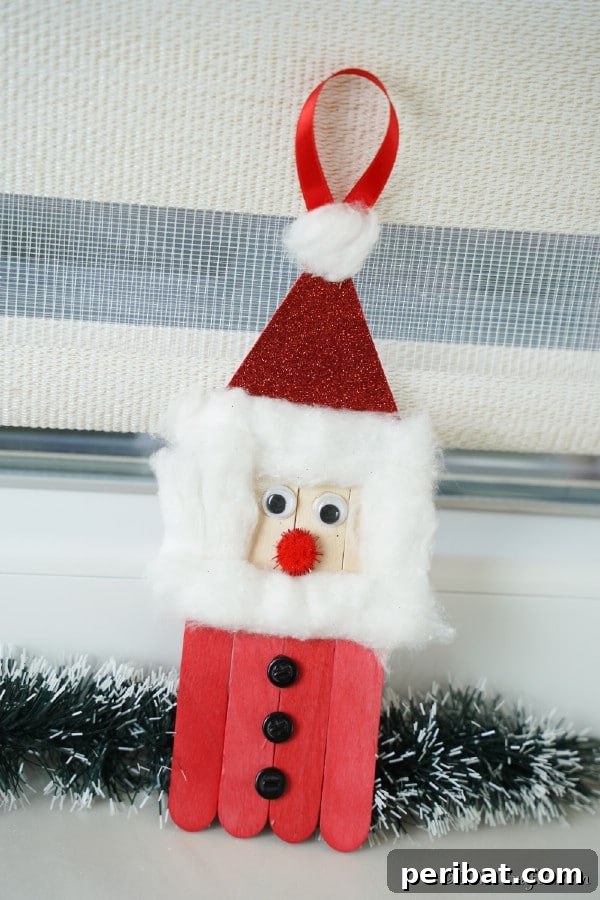 A craft stick Santa ornament sitting on a windowsill