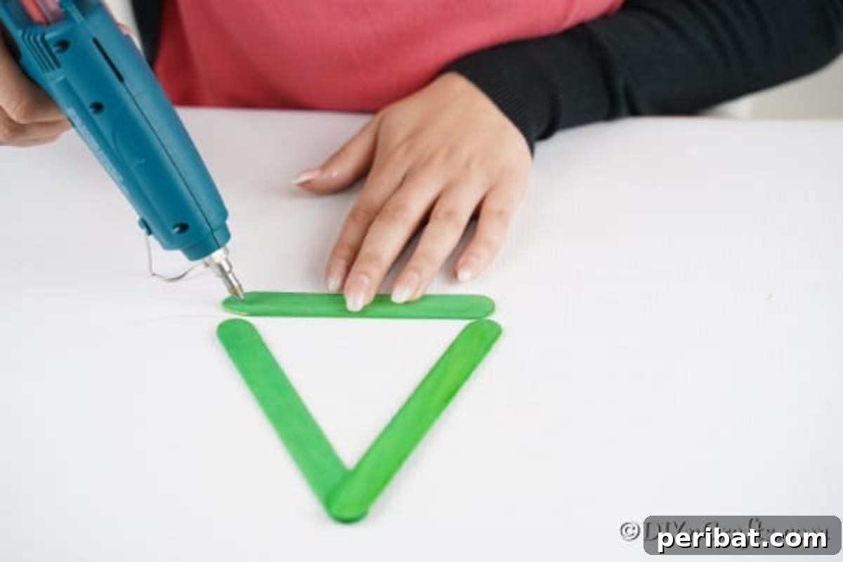 Gluing the green craft sticks together to create a Christmas tree shape