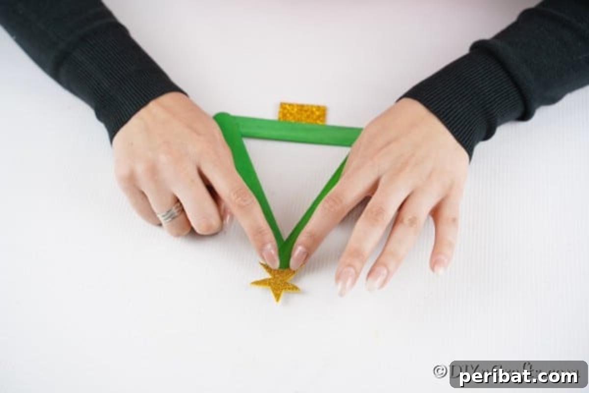 Adding the gold star to the top of the holiday craft stick tree
