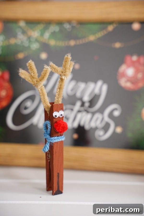 Transform Clothespins Into Adorable Reindeer Ornaments 17 A clothespin reindeer sitting in front of a merry christmas sign