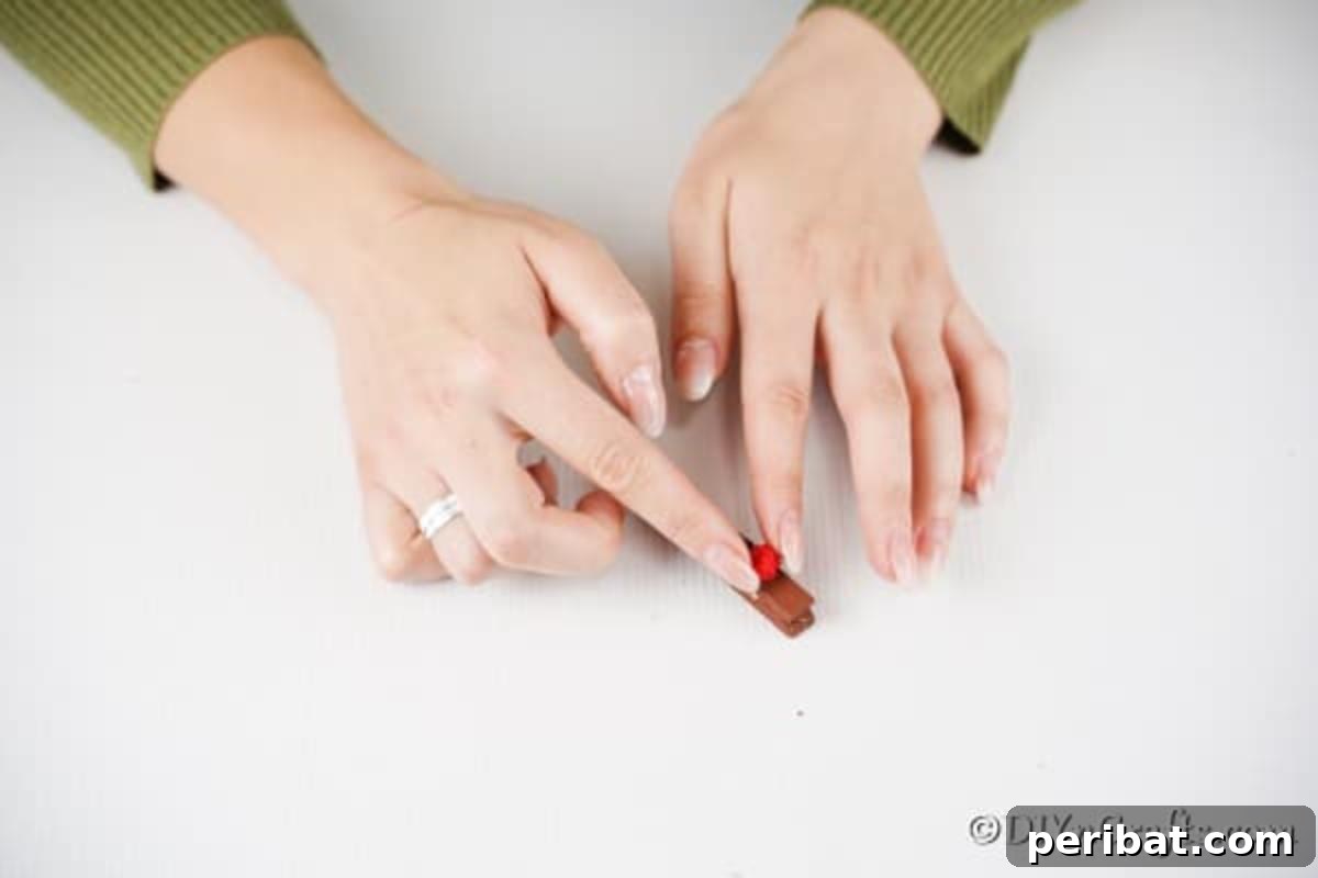 Transform Clothespins Into Adorable Reindeer Ornaments 9 Gluing a red pom pom onto a clothespin reindeer