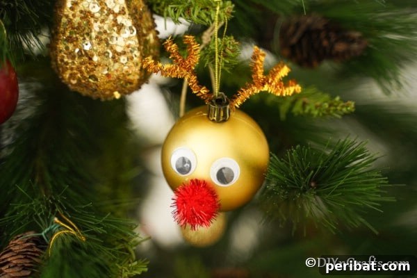 A gold shiny Rudolf the red-nosed reindeer Christmas ornament on a Christmas tree, sparkling among other decorations.