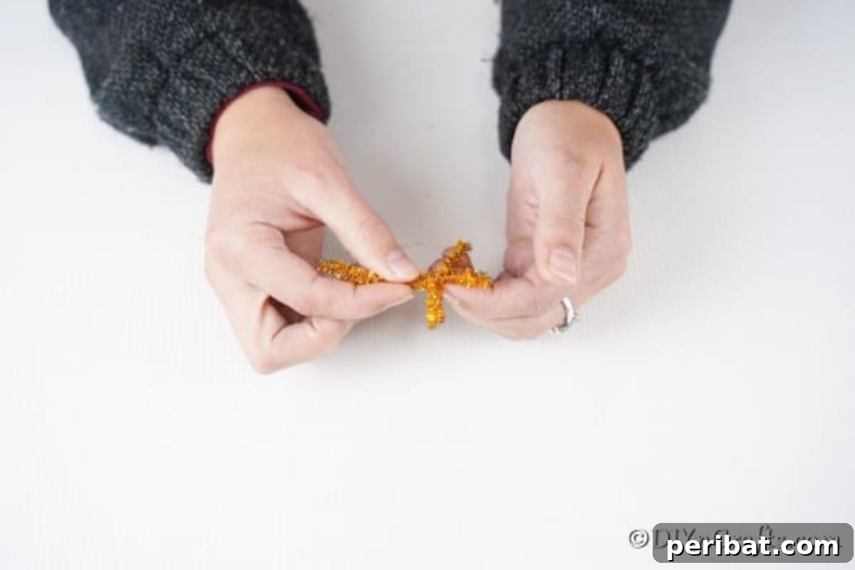 Rudolph's Dazzling Christmas Tree Bauble 7 Detailed step of making antlers from pipe cleaners, demonstrating the bending and twisting process for realistic reindeer horns.