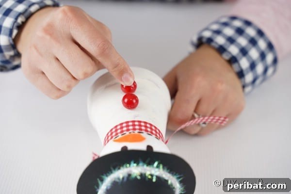 Adding berries on body of snowman