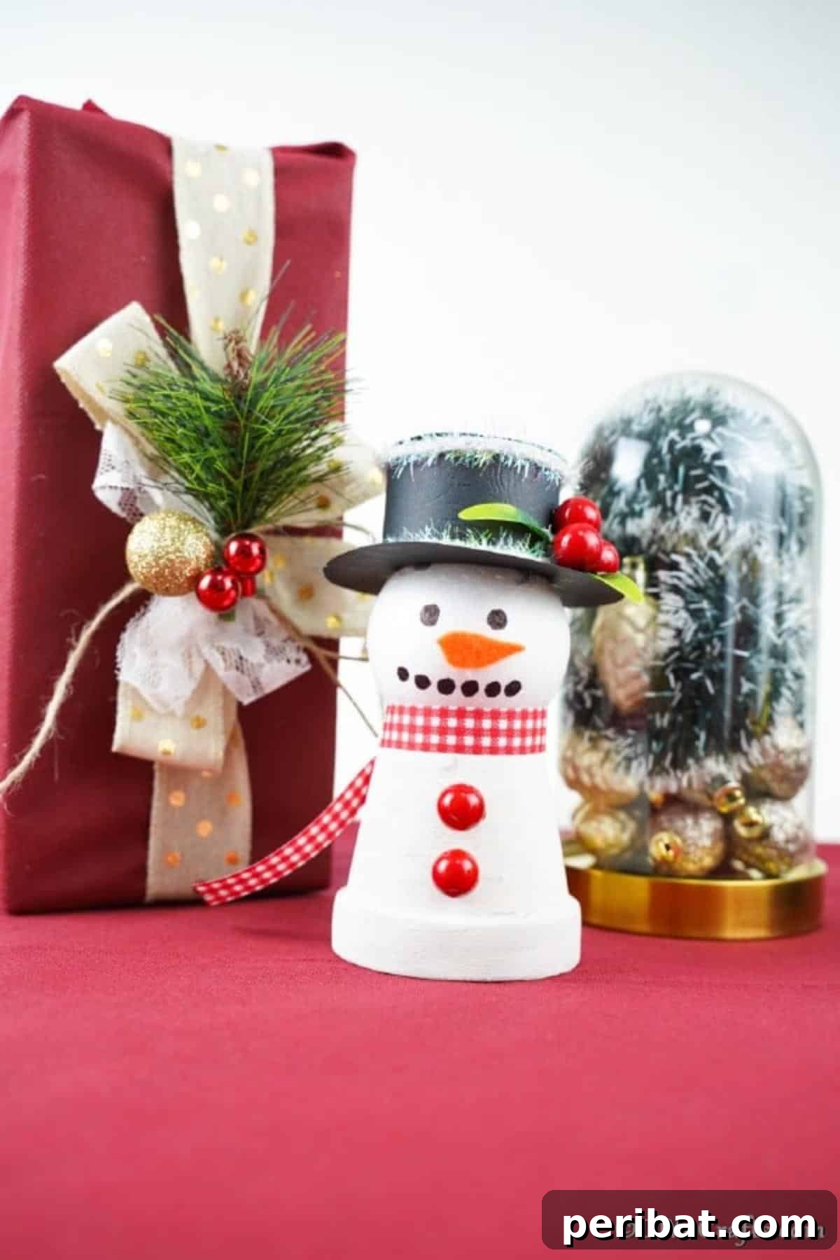 Up close picture of clay pot snowman decoar on a red tablecloth