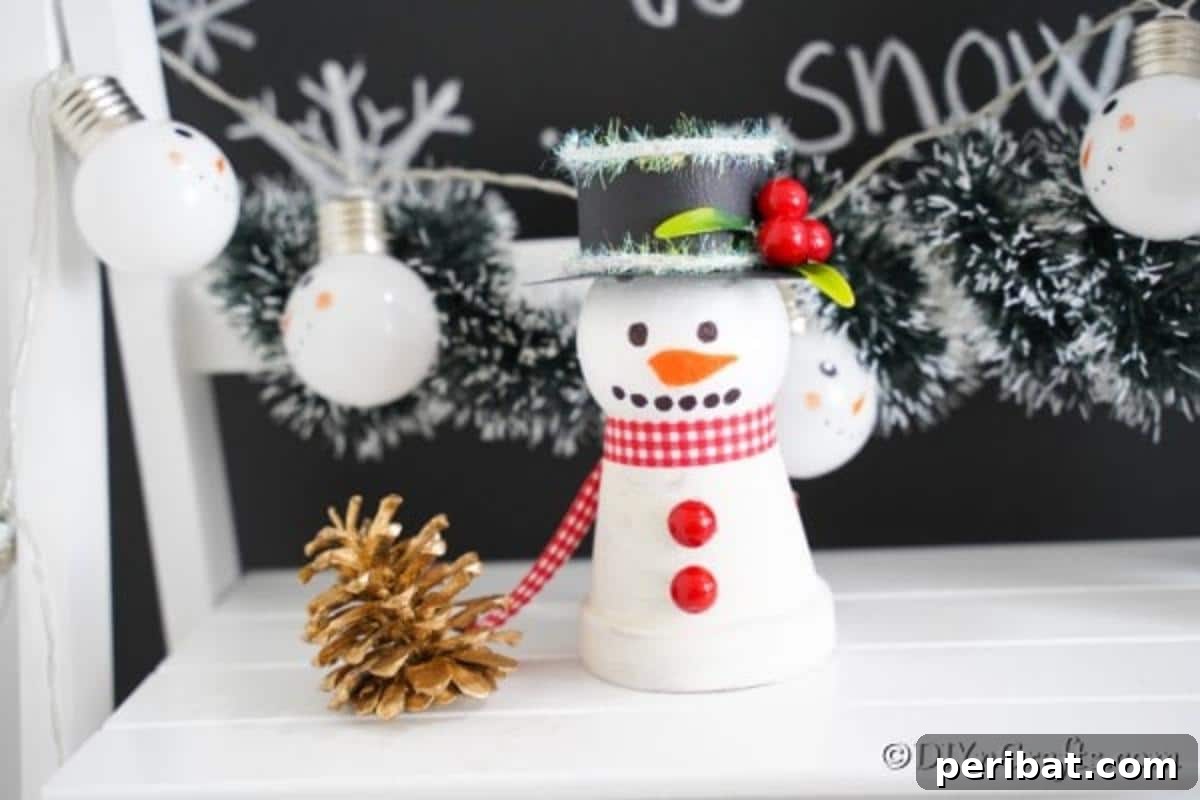 Clay pot snowman decoration on a white shelf in front of chalkboard let it snow sign