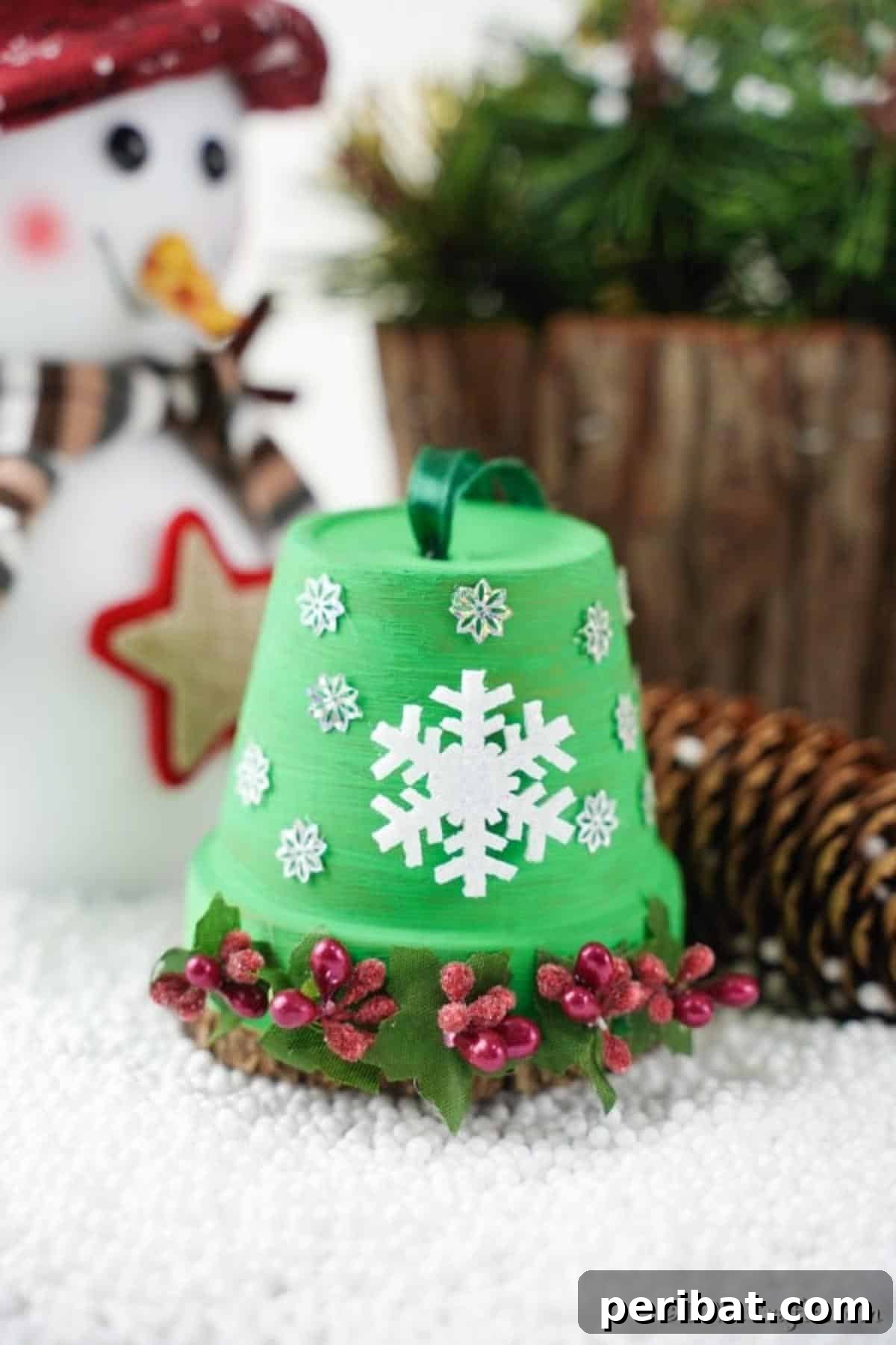 Craft Your Own Adorable Christmas Bell Ornaments 5 Close-up of a rustic DIY Christmas Bell decoration adorned with a white snowflake, red berries, and green leaves