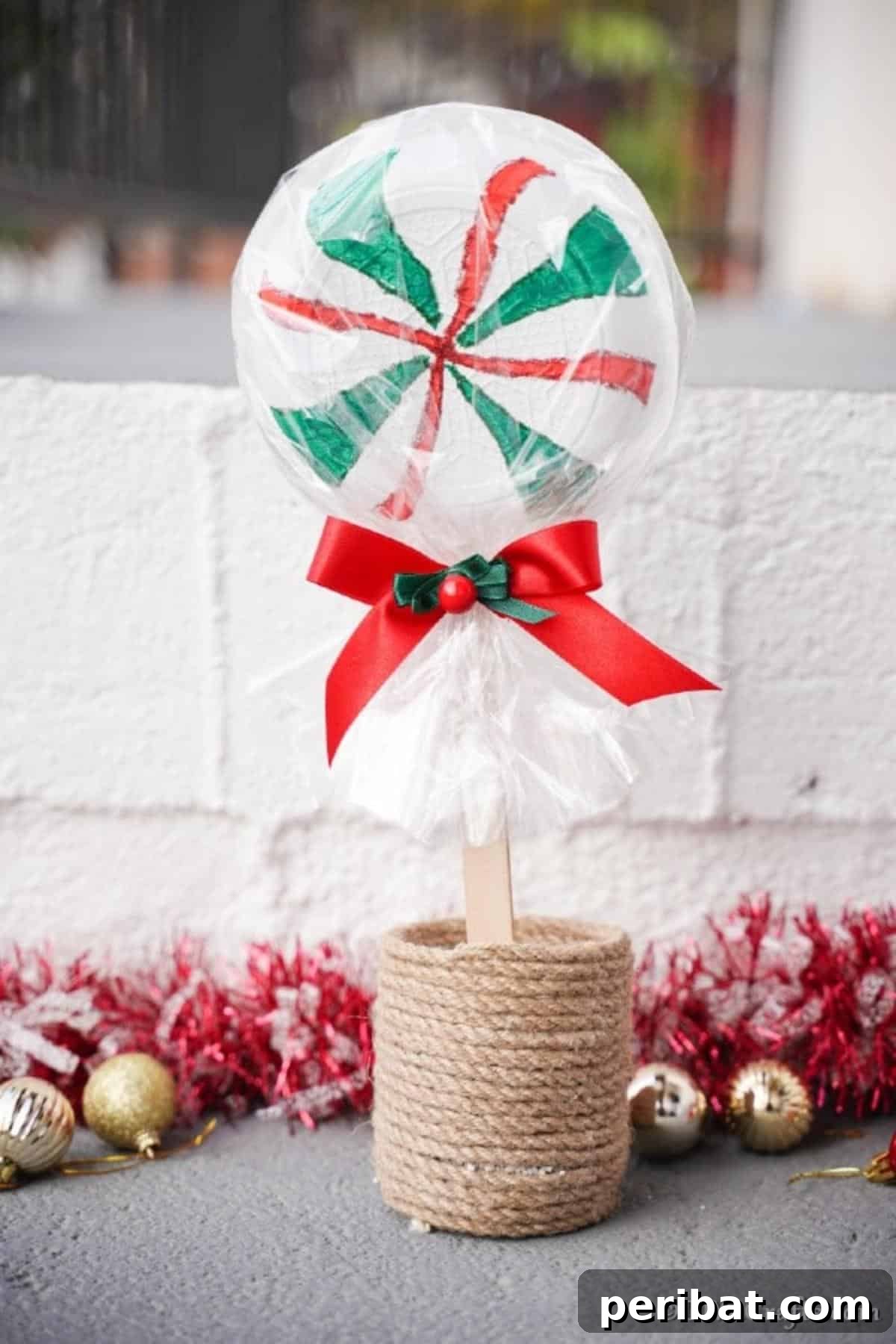 A giant lollipop in a small planter in front of a brick wall for Christmas