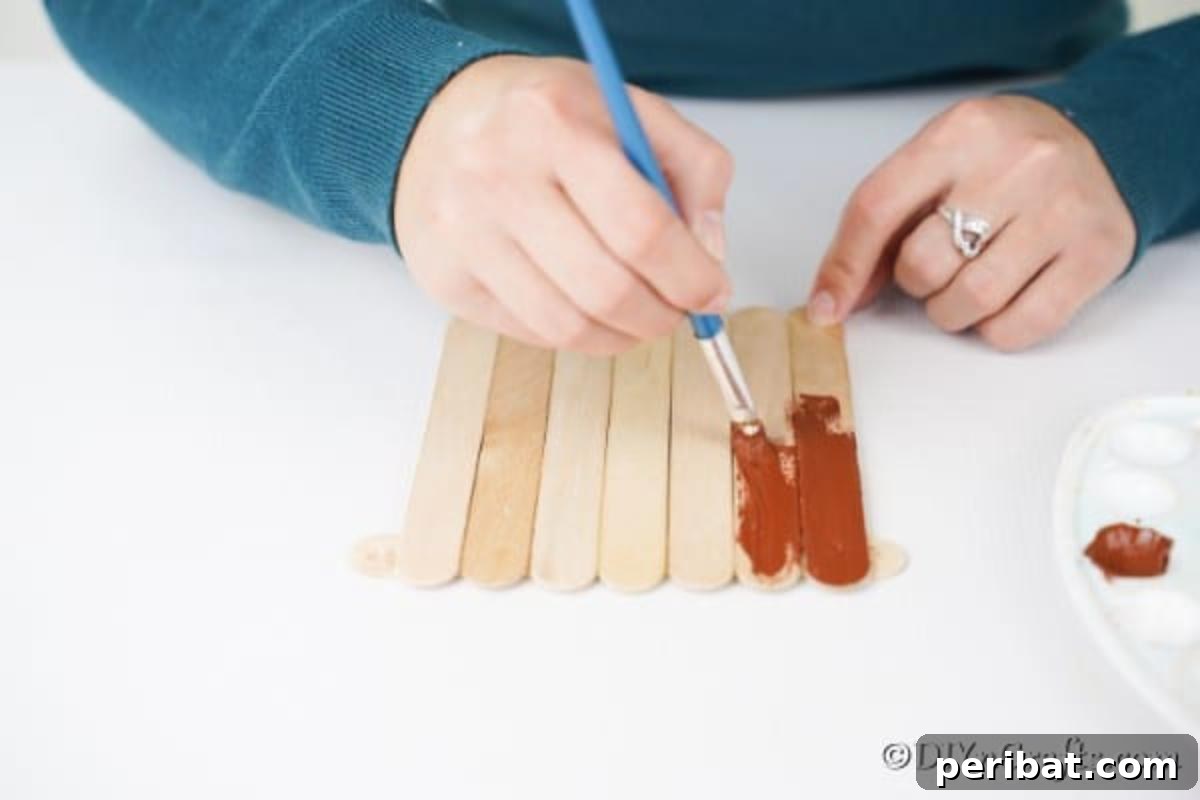 Whimsical Wooden Gingerbread House Charm 11 Painting the assembled craft sticks brown for the main body of the gingerbread house