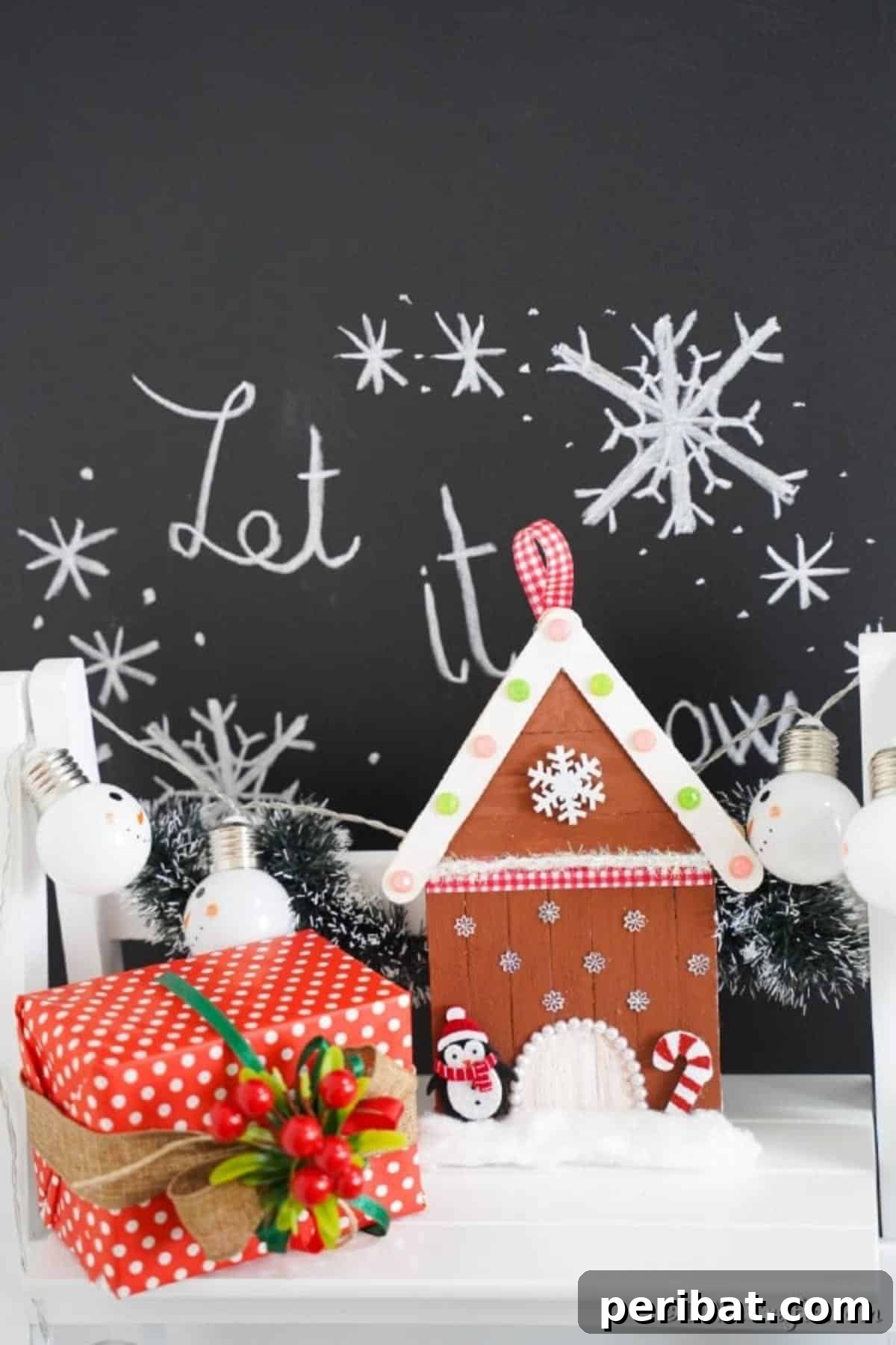 Whimsical Wooden Gingerbread House Charm 4 Decorated craft stick gingerbread house ornament on a white shelf in front of a festive holiday sign, showcasing its charming details