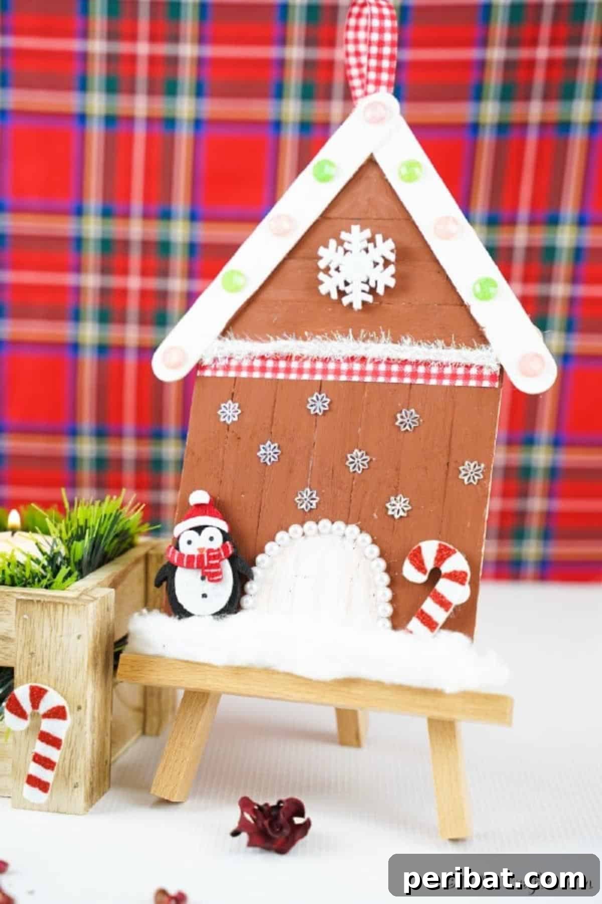 Whimsical Wooden Gingerbread House Charm 5 Close-up of a charming popsicle stick gingerbread house ornament set against a festive plaid backdrop