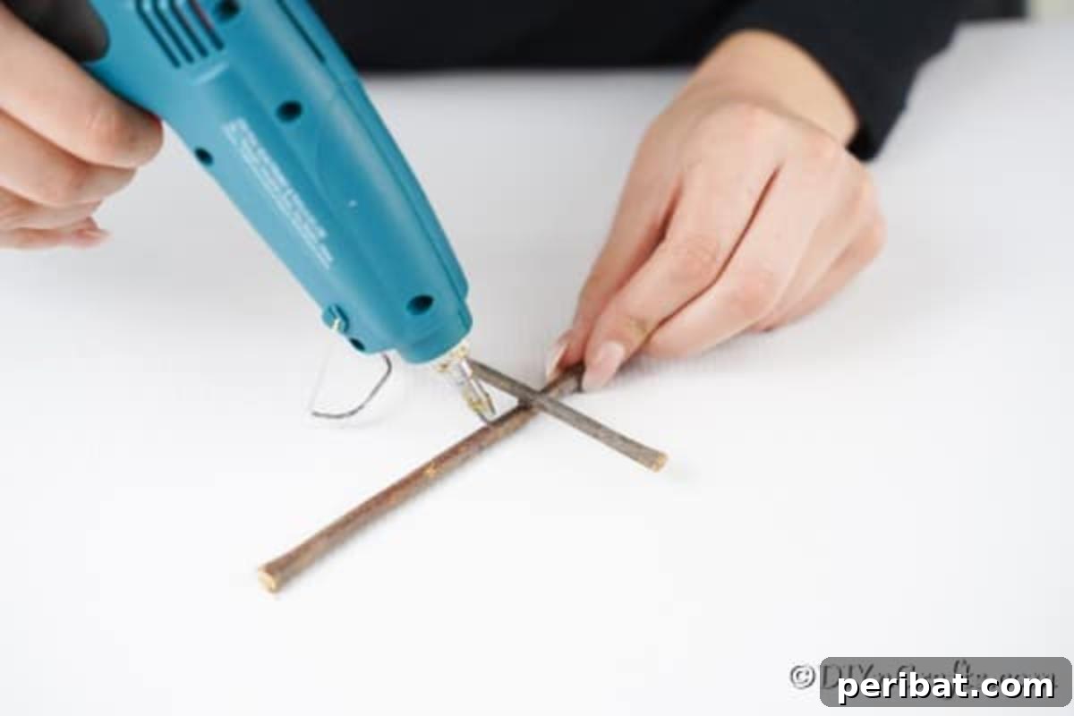 DIY Rustic Twig and Branch Christmas Ornaments 12 Carefully laying and gluing twigs in place to create the distinctive shape of a rustic Christmas tree ornament.