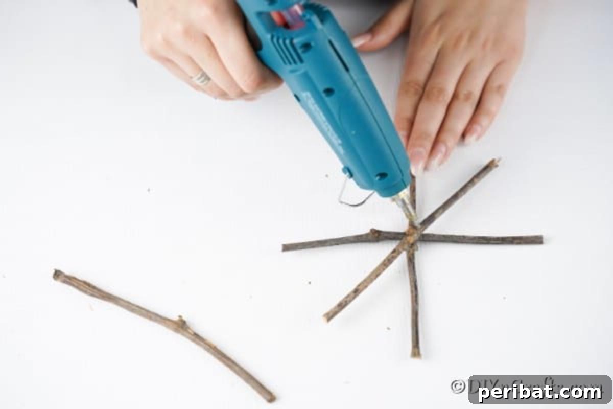 DIY Rustic Twig and Branch Christmas Ornaments 15 Carefully gluing together four twigs to form the central star shape of a rustic snowflake ornament.