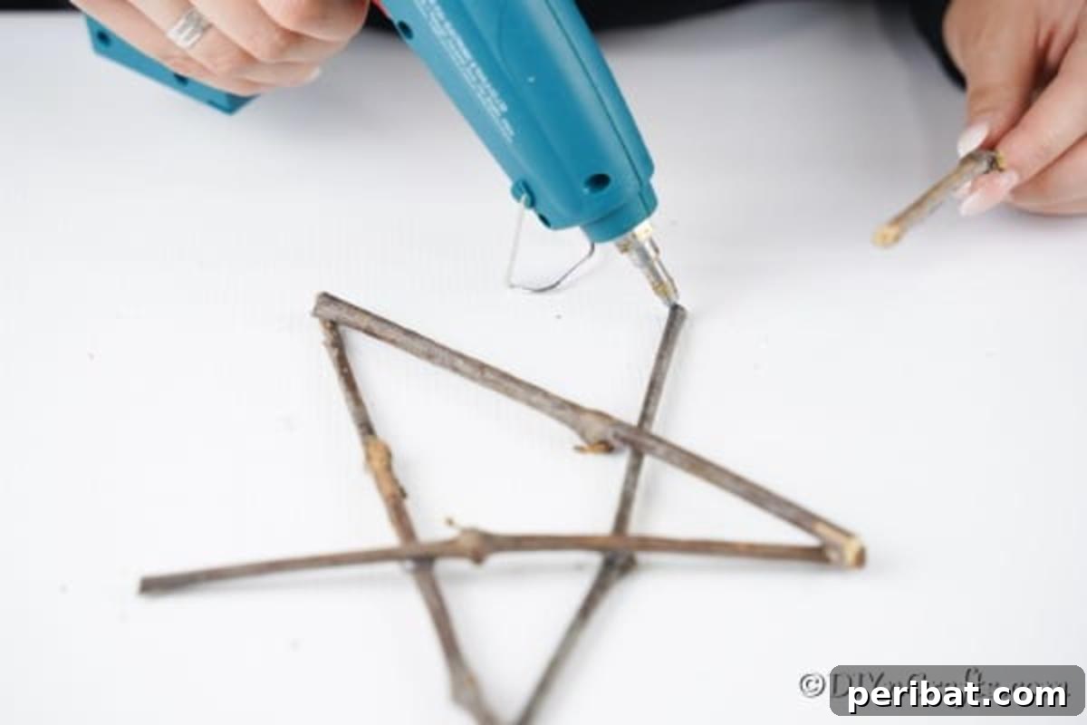 DIY Rustic Twig and Branch Christmas Ornaments 8 Twigs being carefully glued together to form the intricate shape of a rustic star ornament.