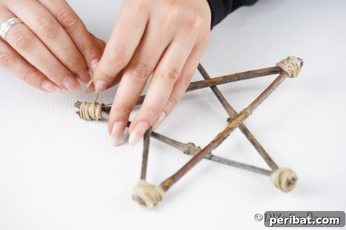 DIY Rustic Twig and Branch Christmas Ornaments 9 Rustic thread being meticulously added to the edges of a star ornament, enhancing its natural, handmade appeal.